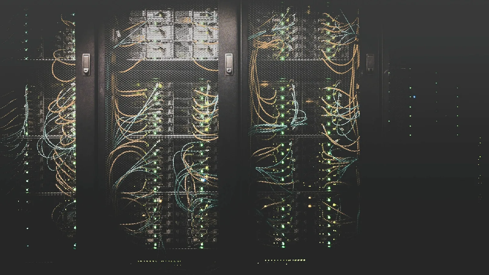 Dark server racks with glowing network cabling inside a communications room
