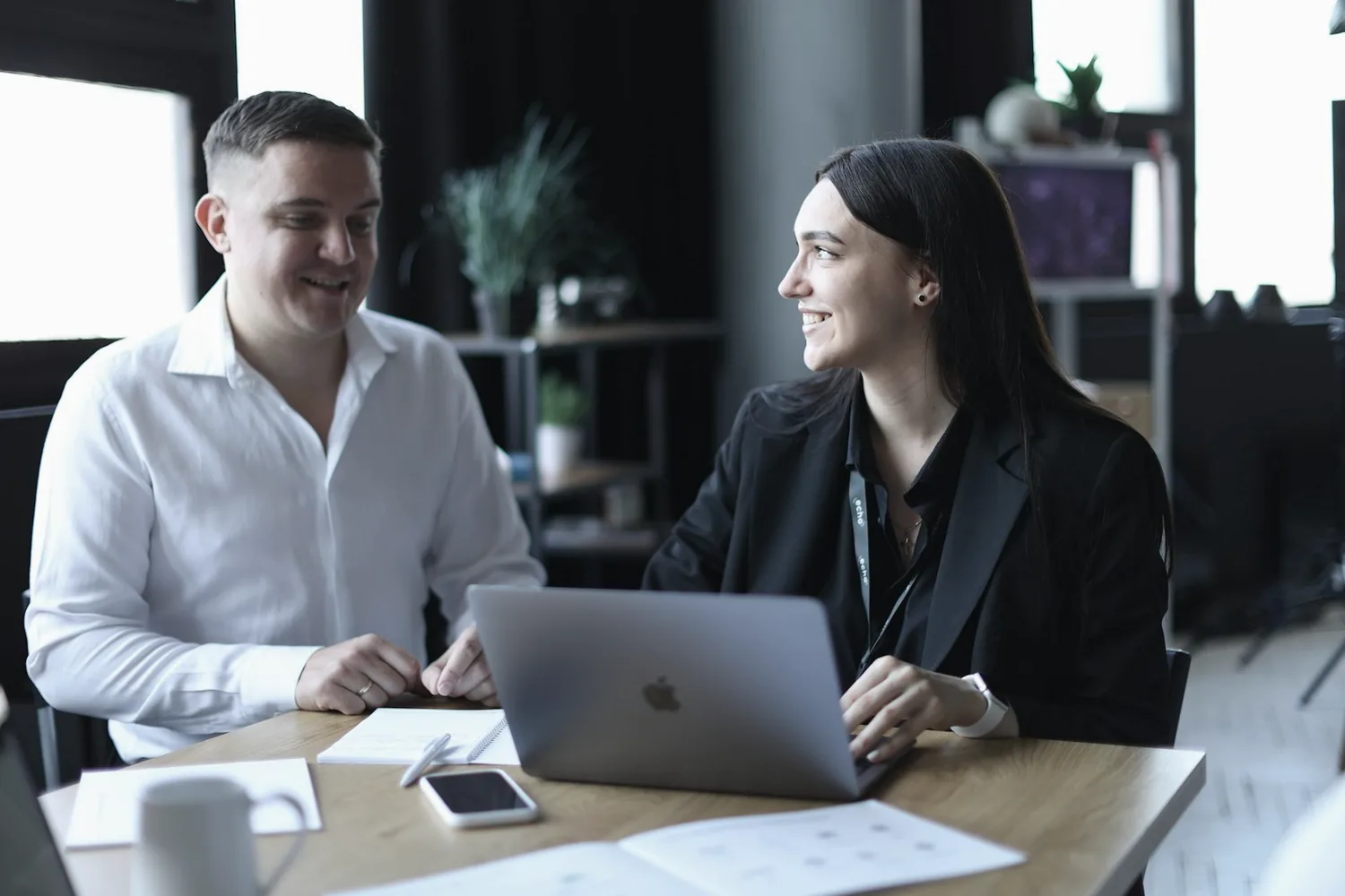 Two people looking at a laptop screen together in an office