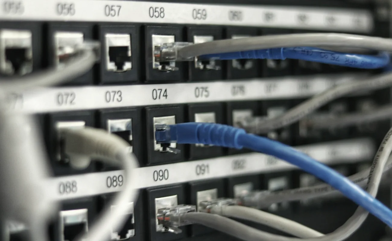 Numbered network patch panel with ports labelled in a wall-mounted rack
