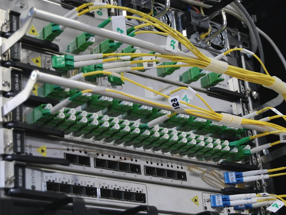 Fibre patch panel with green and yellow fibre leads in a comms rack